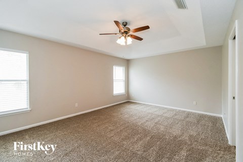 A spacious room with a ceiling fan and carpeted floor.