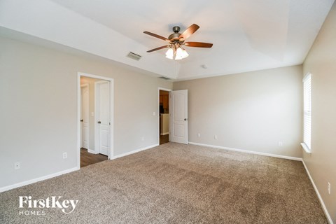 A spacious room with a ceiling fan and carpeted floor.