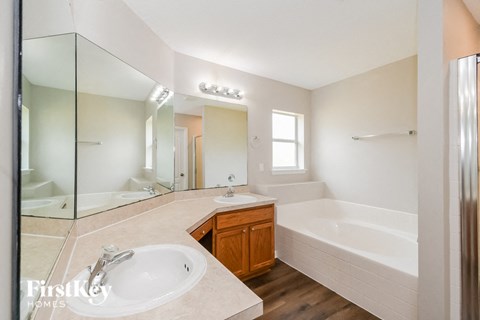 A bathroom with a sink, mirror, and bathtub.