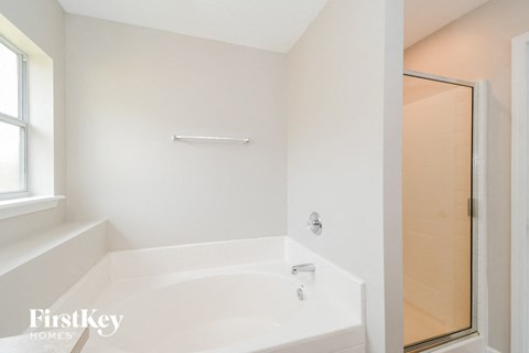 A white bathroom with a tub and a door.