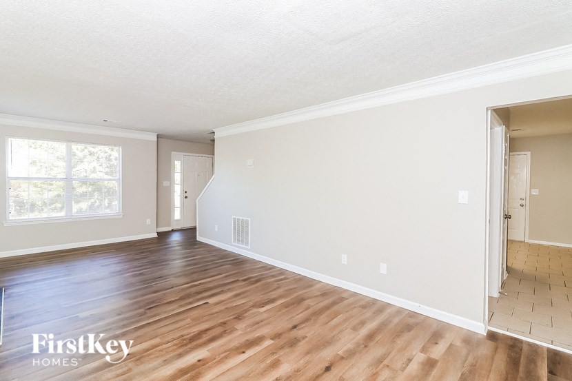 the living room and dining room with hardwood floors and white walls