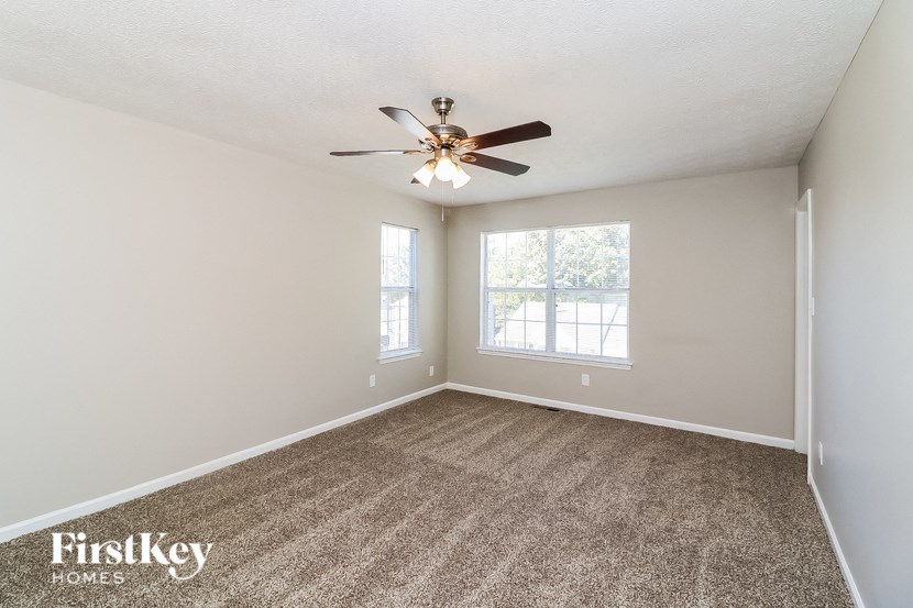 an empty living room with a ceiling fan and a window