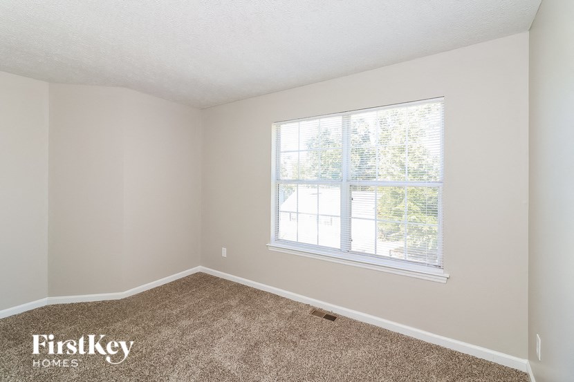 a bedroom with carpet and a large window
