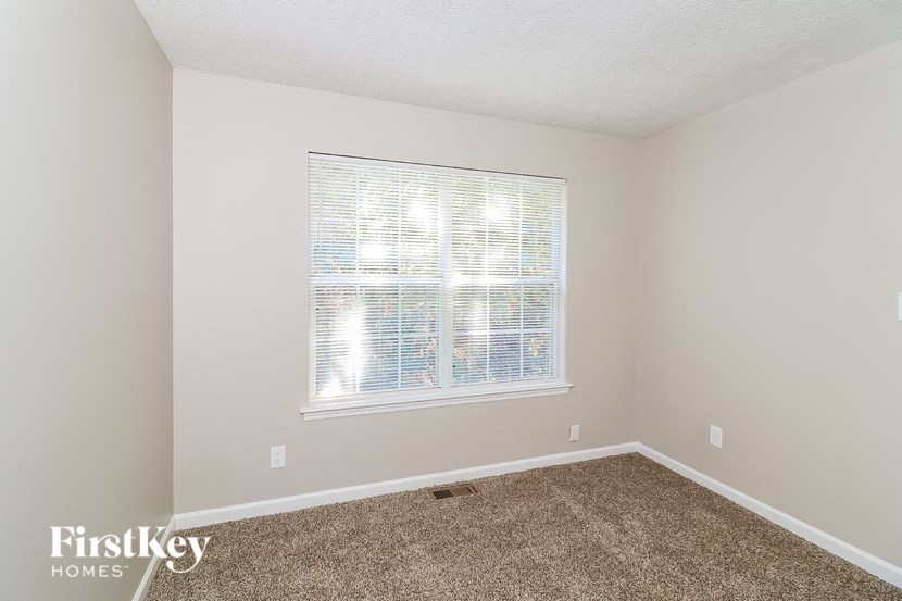 a bedroom with a large window and a carpeted floor