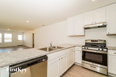 a kitchen with white cabinets and granite counter tops and stainless steel appliances