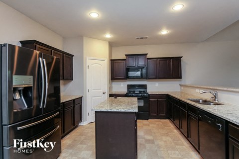 A kitchen with a black fridge and cabinets by FirstKey Homes.