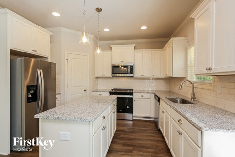 A kitchen with white cabinets and a granite countertop.