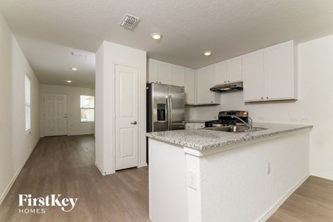 A kitchen with a refrigerator, stove, and cabinets.