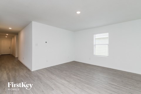 the living room of a house with white walls and wood floors