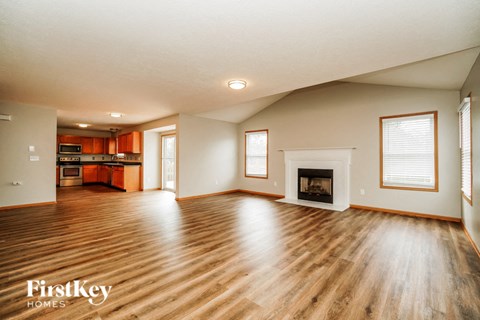 A spacious living room with wood flooring and a fireplace.