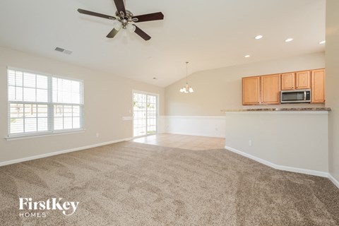 an empty living room and kitchen with a ceiling fan