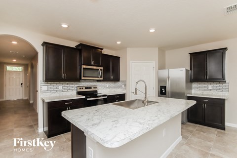 A kitchen with a marble countertop and black cabinets.
