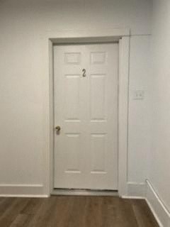 A white door with a gold handle is in a room with a wooden floor.