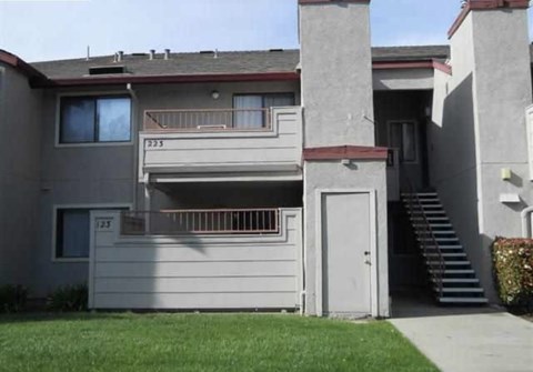 the front of a gray house with a white door