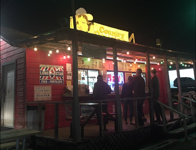 a group of people standing outside of a restaurant at night