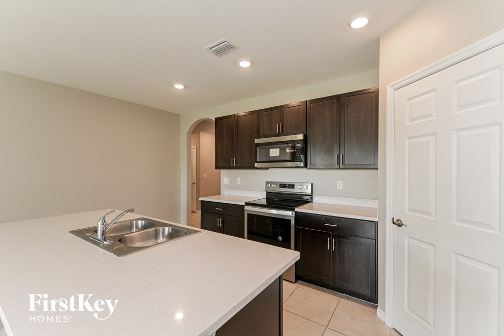 A kitchen with a sink, stove, and cabinets.