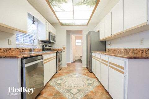 a kitchen with white cabinets and granite counter tops and stainless steel appliances
