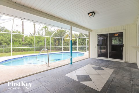 a swimming pool in a house with a glass door and a patio