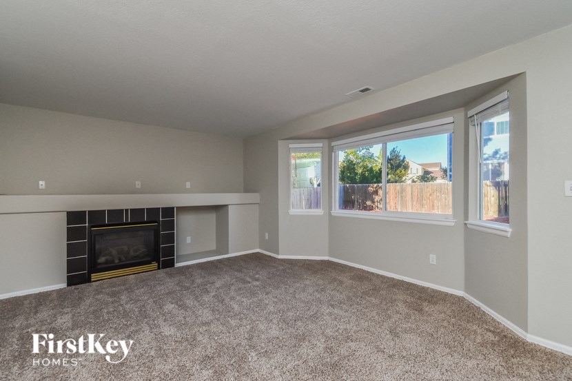 an empty living room with a fireplace and windows