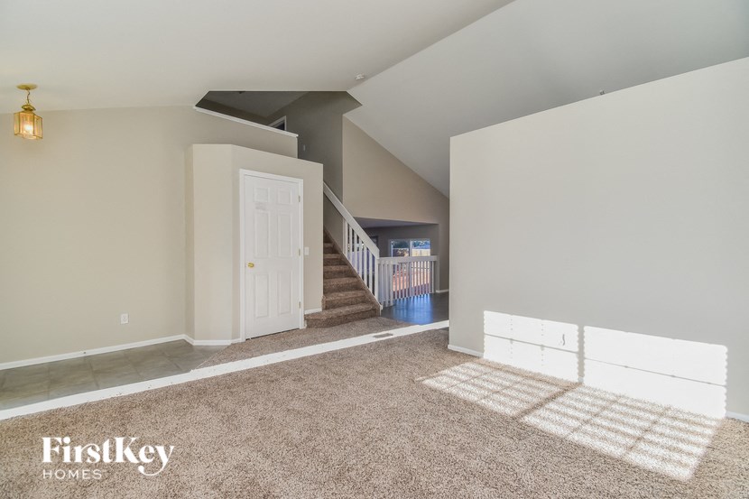 a living room with a carpeted staircase and a white door