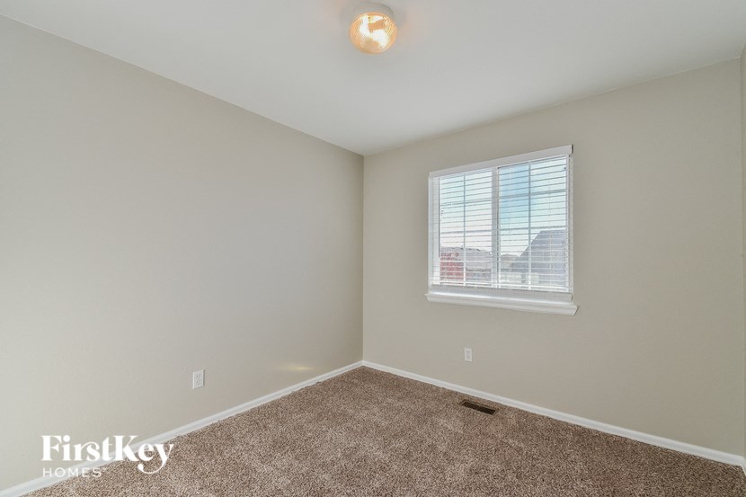 a bedroom with beige carpet and a window