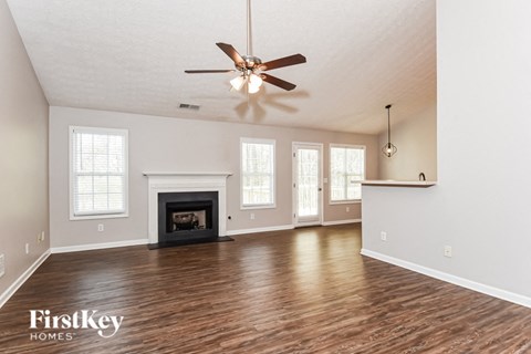an empty living room with a ceiling fan and a fireplace
