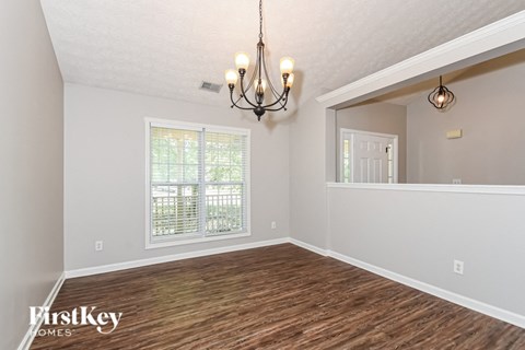 the spacious living room with a large window and a chandelier