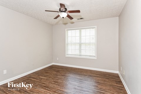 a bedroom with a ceiling fan and wood floors