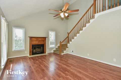 A spacious living room with a fireplace and a staircase.