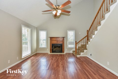 A spacious room with a fireplace and wooden floors.
