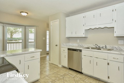 A kitchen with white cabinets and a tiled floor.