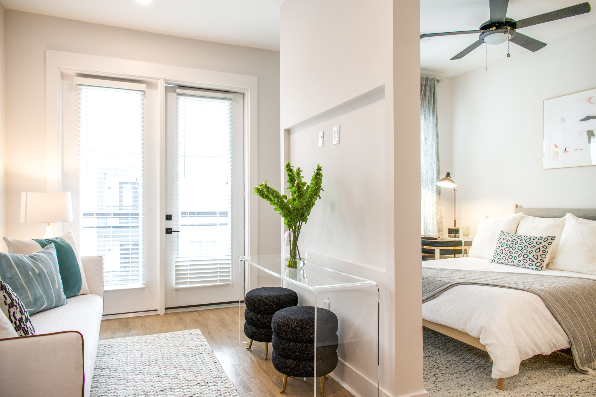 a bedroom with a bed and a living room with a ceiling fan