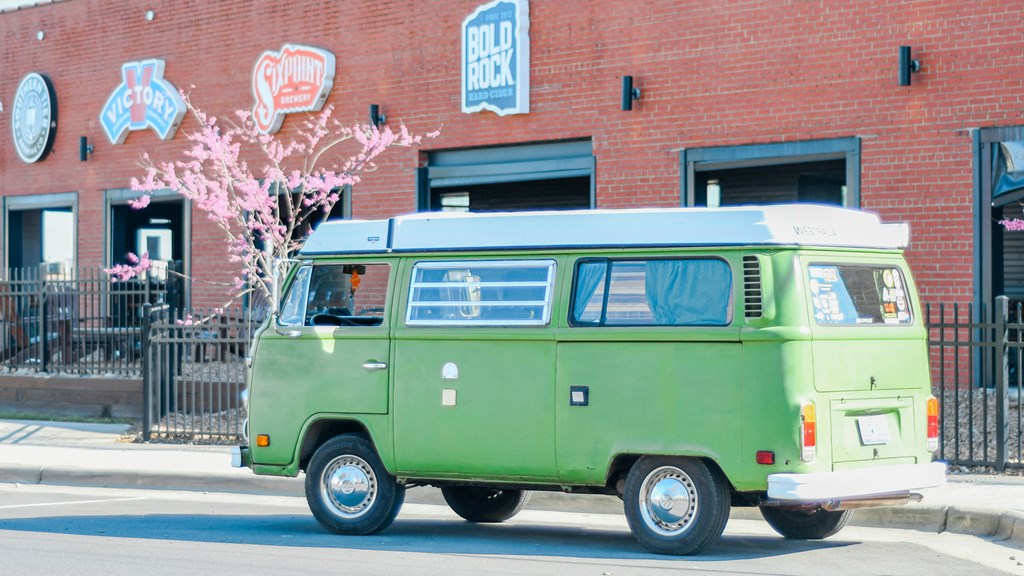 a green van parked on the street in front of a brick building