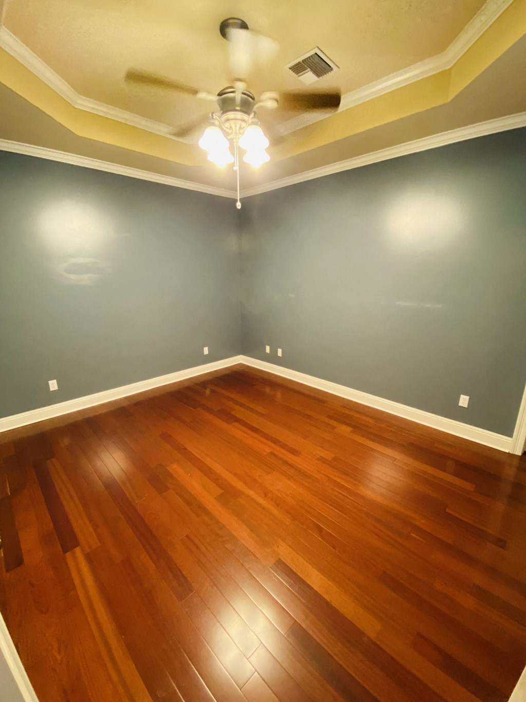 a empty living room with wood floors and a ceiling fan