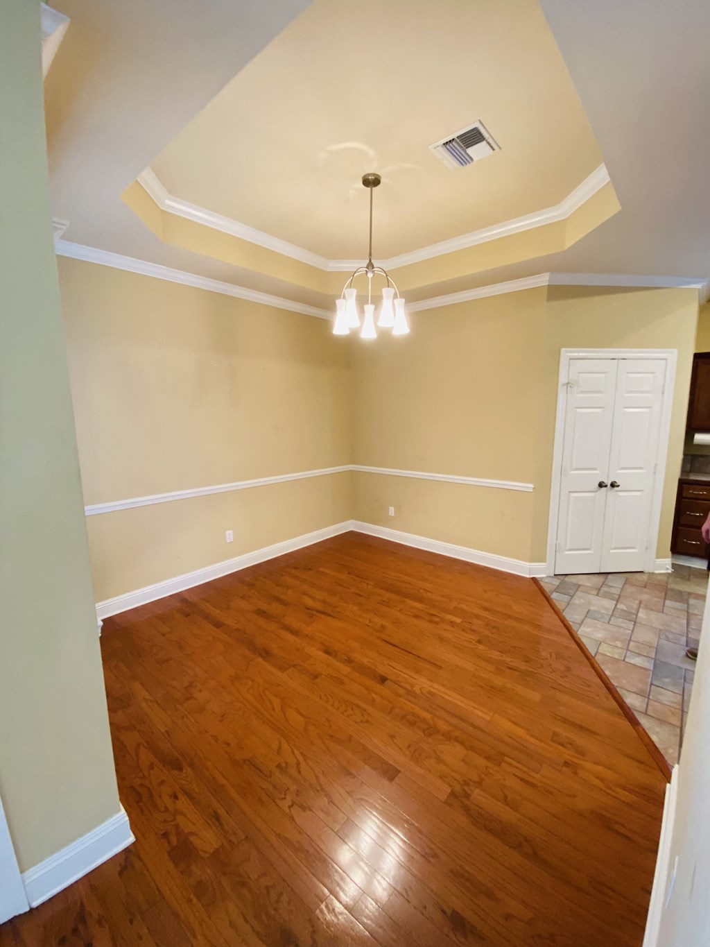 an empty living room with wooden floors and a chandelier