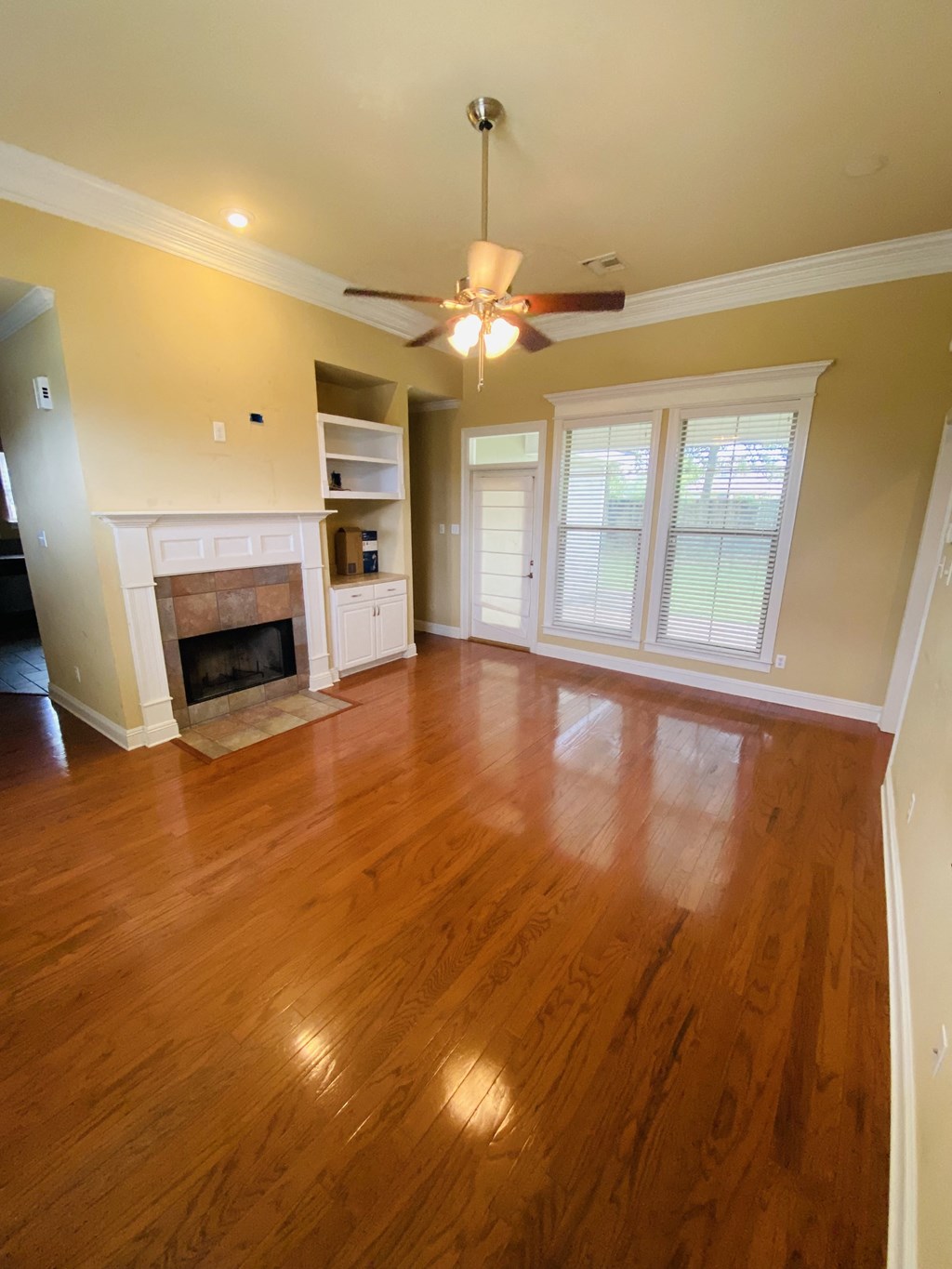 an empty living room with a fireplace and a ceiling fan