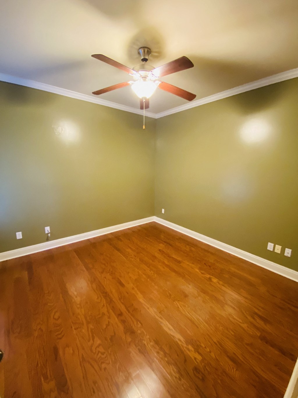 a empty room with a ceiling fan and wood floors