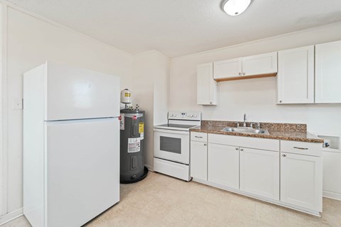 a kitchen with white cabinets and appliances and a refrigerator