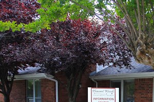 a front yard with flowers and trees in front of a house