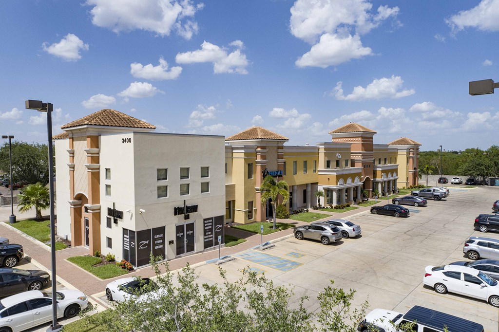 a row of apartment buildings with cars parked in a parking lot