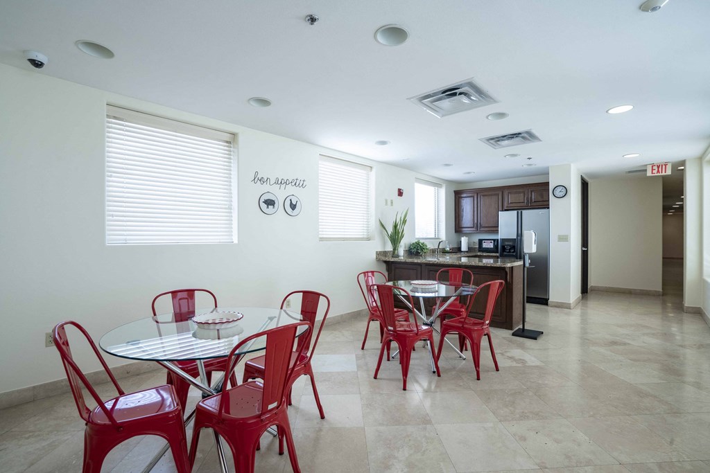 a dining room with red chairs and tables and a kitchen