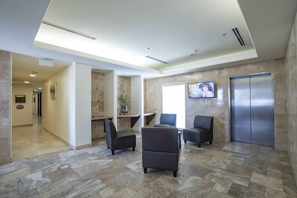 a lobby with chairs and a table and a refrigerator