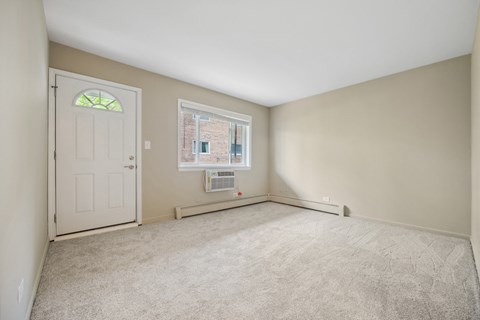 an empty living room with a white door and a window