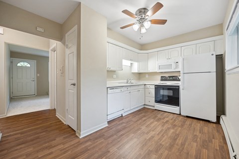 an empty kitchen with white cabinets and a ceiling fan