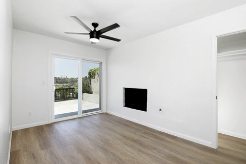 an empty living room with a ceiling fan and a sliding glass door