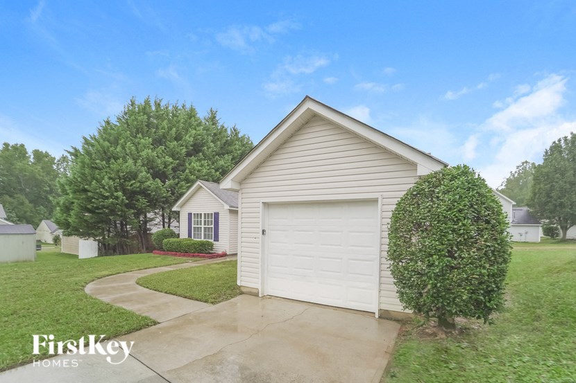 A house with a garage and a tree in front of it.