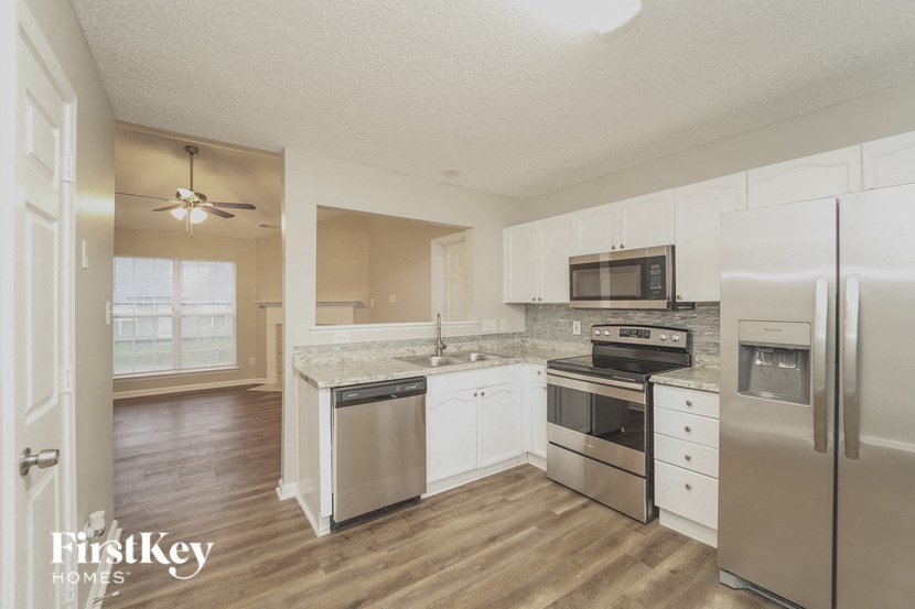A kitchen with a refrigerator, oven, and sink.