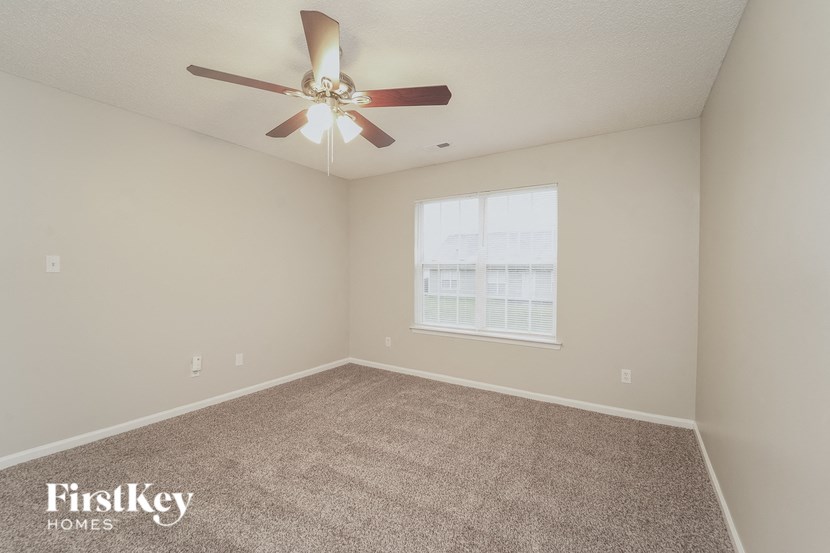 A room with a carpet floor and a ceiling fan.