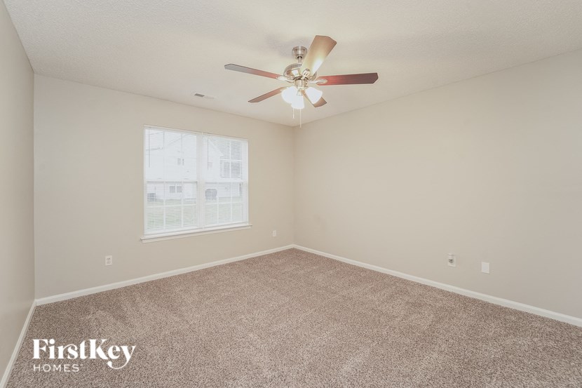 A room with a carpeted floor and a ceiling fan.