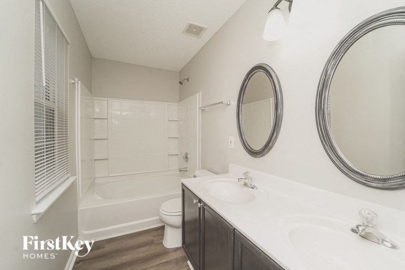 A bathroom with a toilet, sink, and mirror.